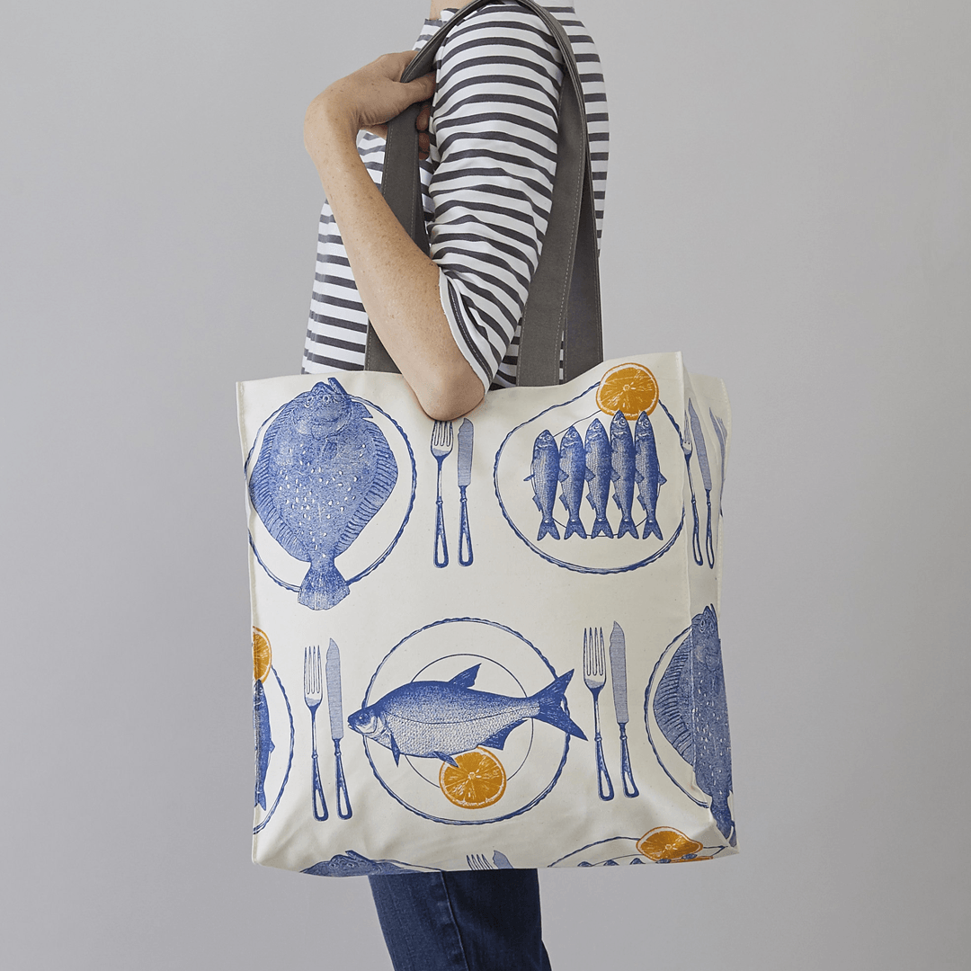 kitchentins - Thornback and Peel Cotton tote bags printed with delft blue dinner plates with fish and bright yellow slices of lemon.