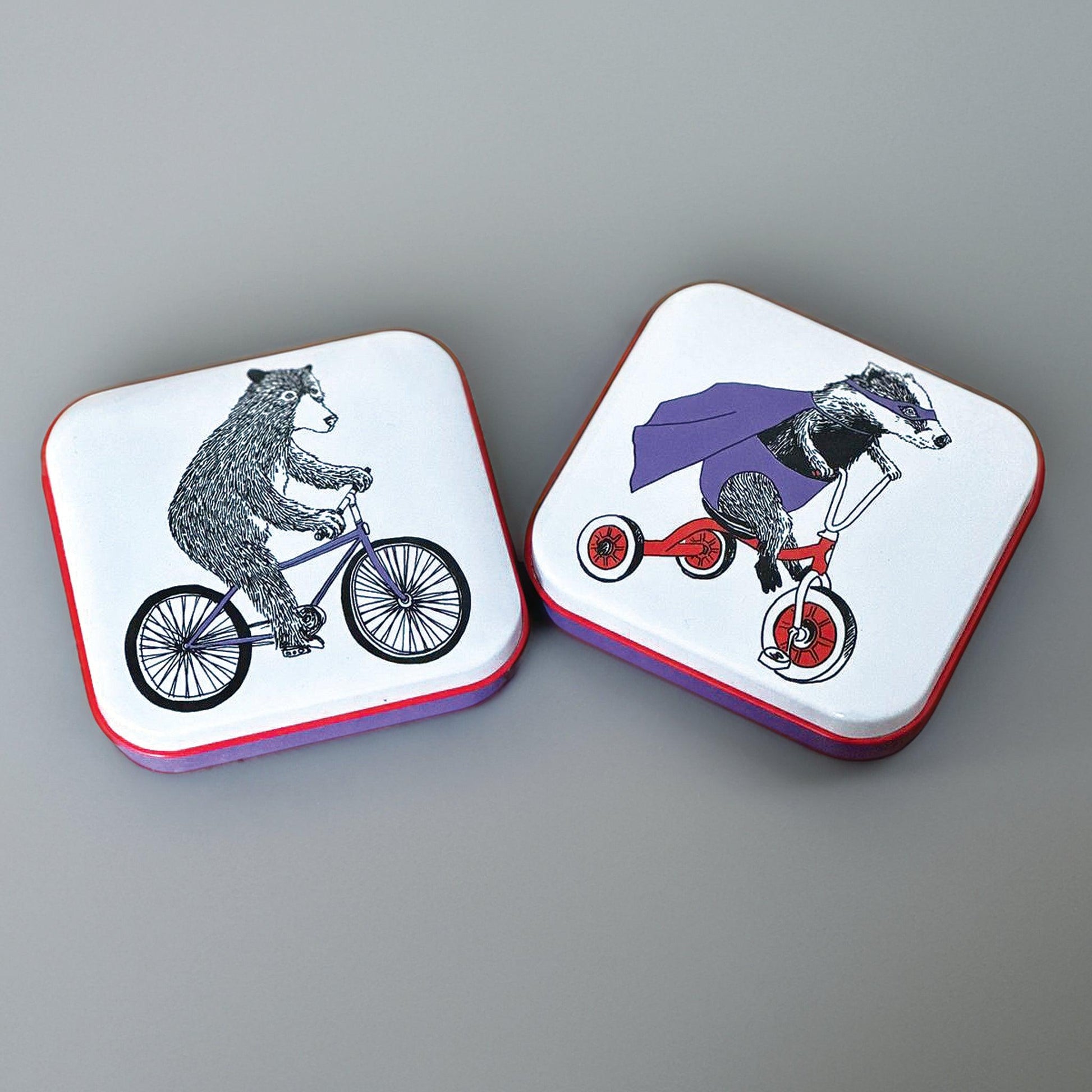 kitchentins - set of two pocket tins, one with a bear riding a bike, and one with a superhero badger riding a tricycle